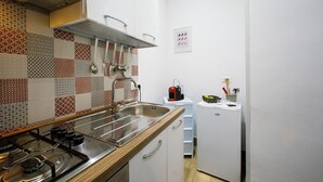 Una cucina compatta con piano cottura a gas, lavello in acciaio inossidabile e schienale decorato.