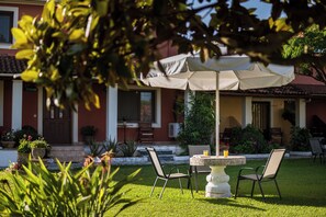 Une terrasse avec une table et des chaises, un parasol et des plantes en pot.