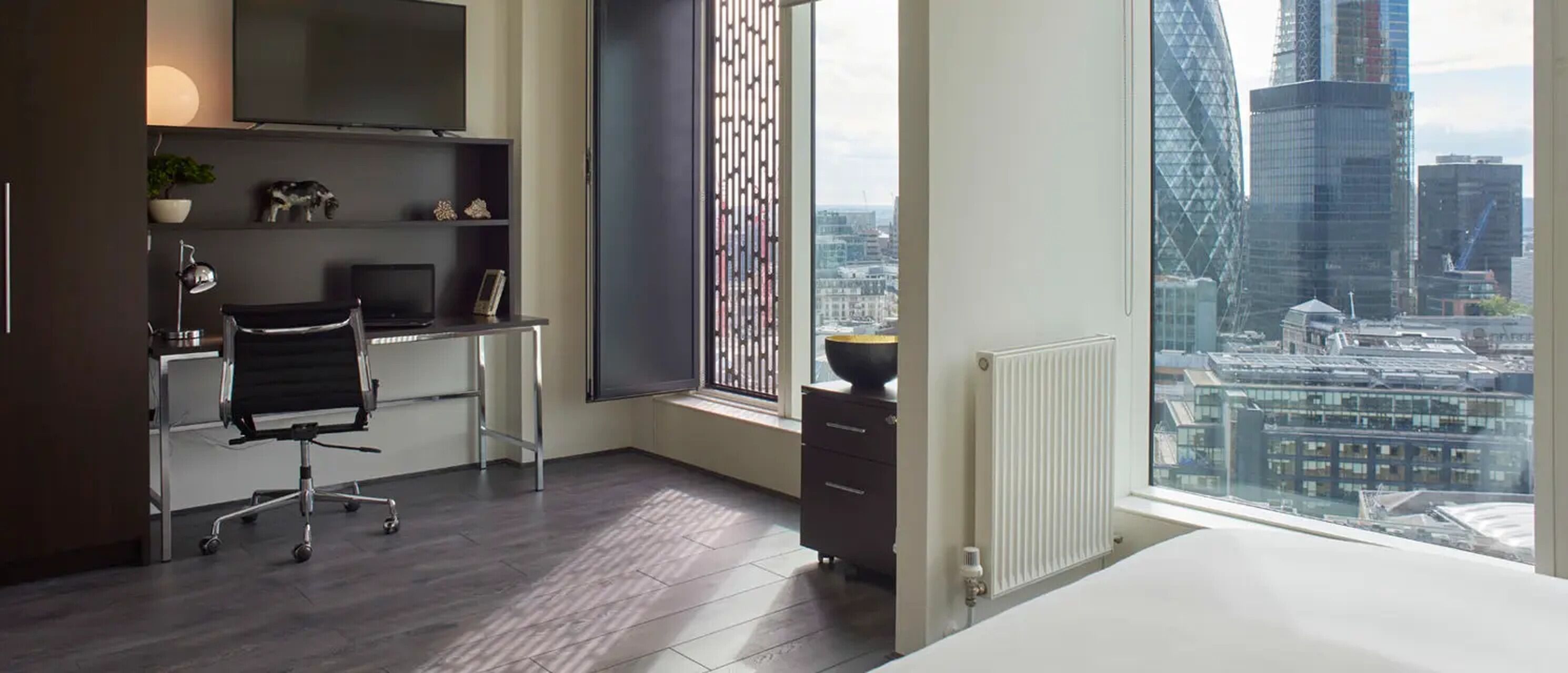A modern office space with a desk, chair, and a large window offering a city view.