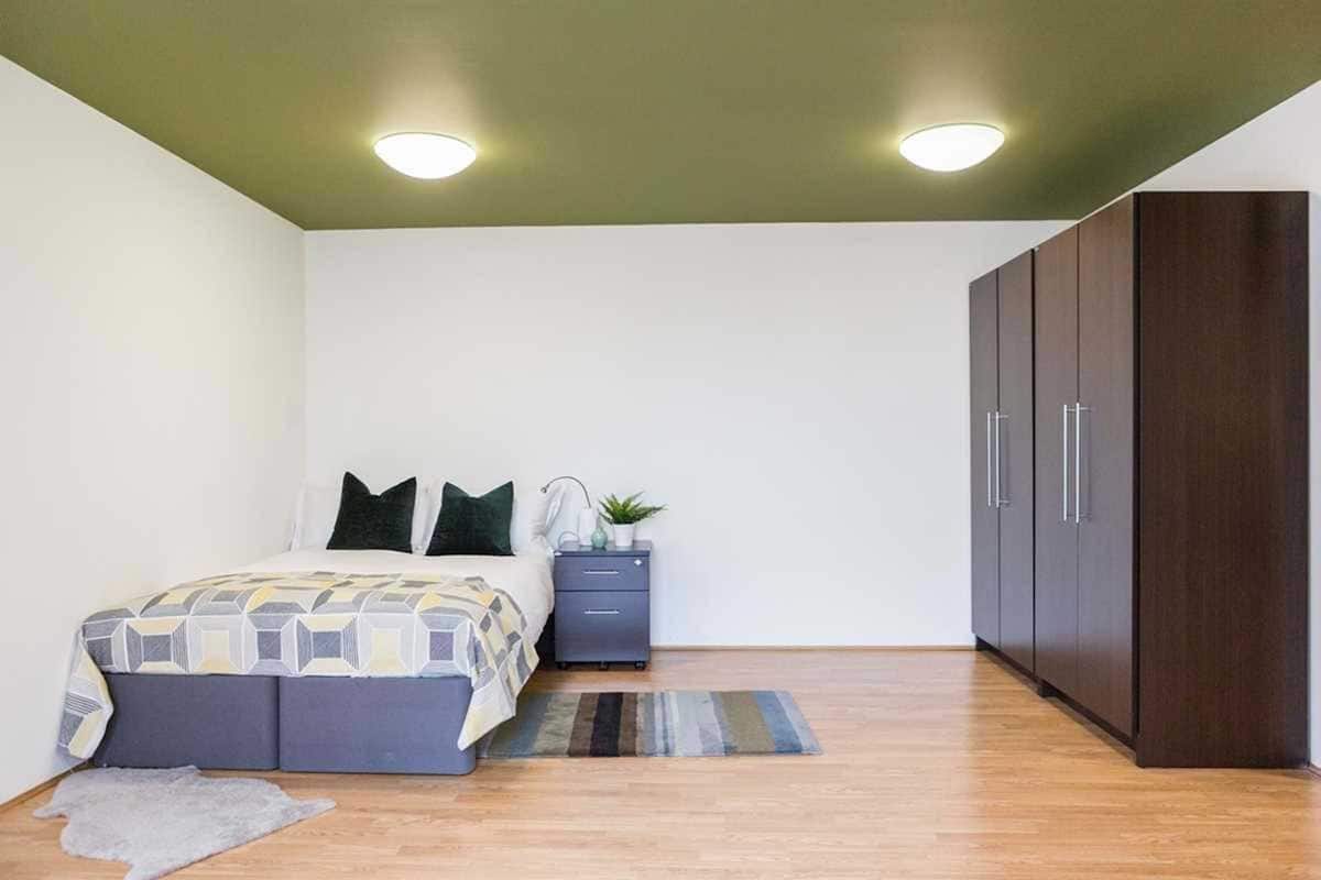 Ein Schlafzimmer mit Bett, Nachttisch, Kleiderschrank und einer kleinen Pflanze.