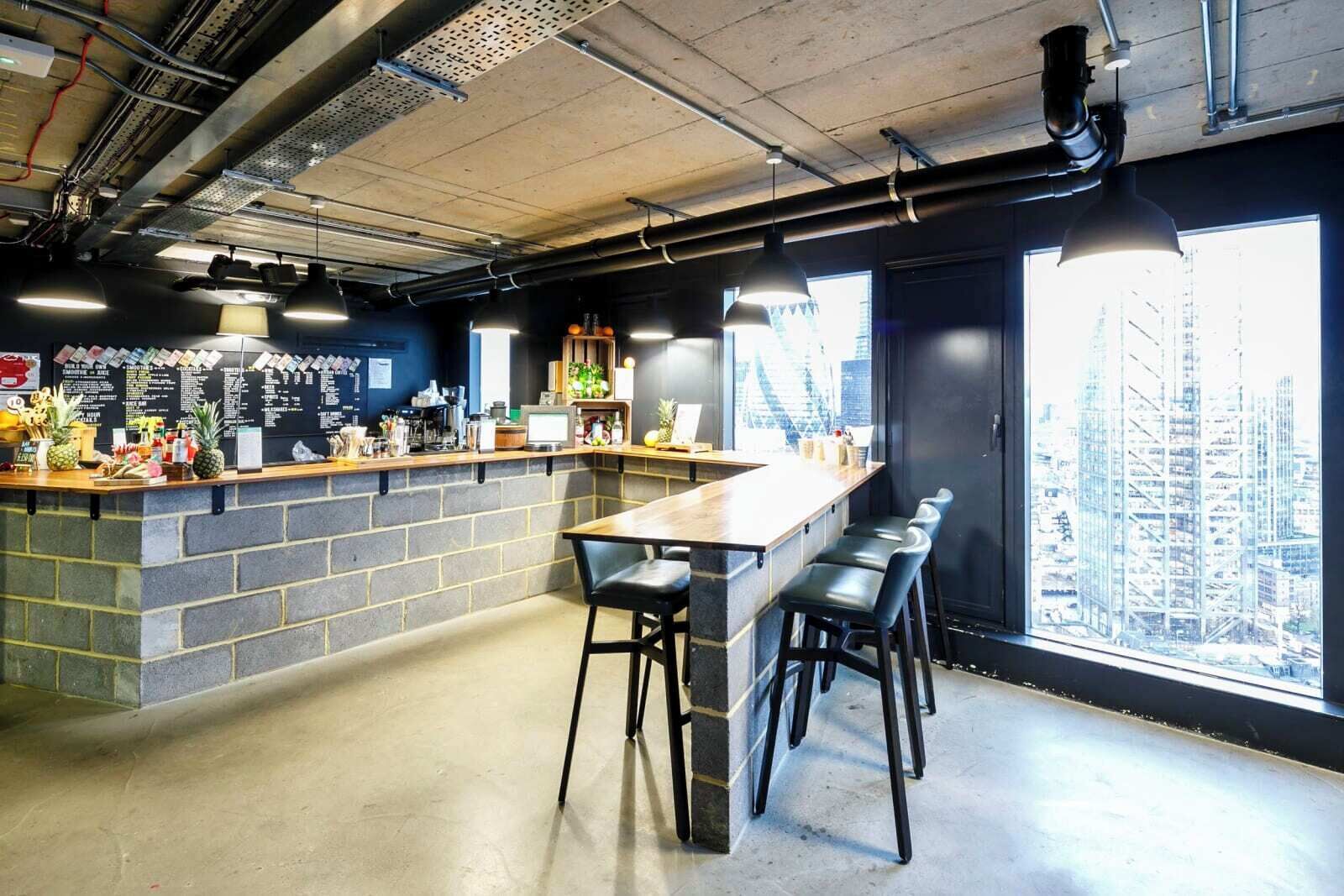 Zona de bar moderna con una barra alargada, taburetes y vistas a la ciudad a través de amplios ventanales.