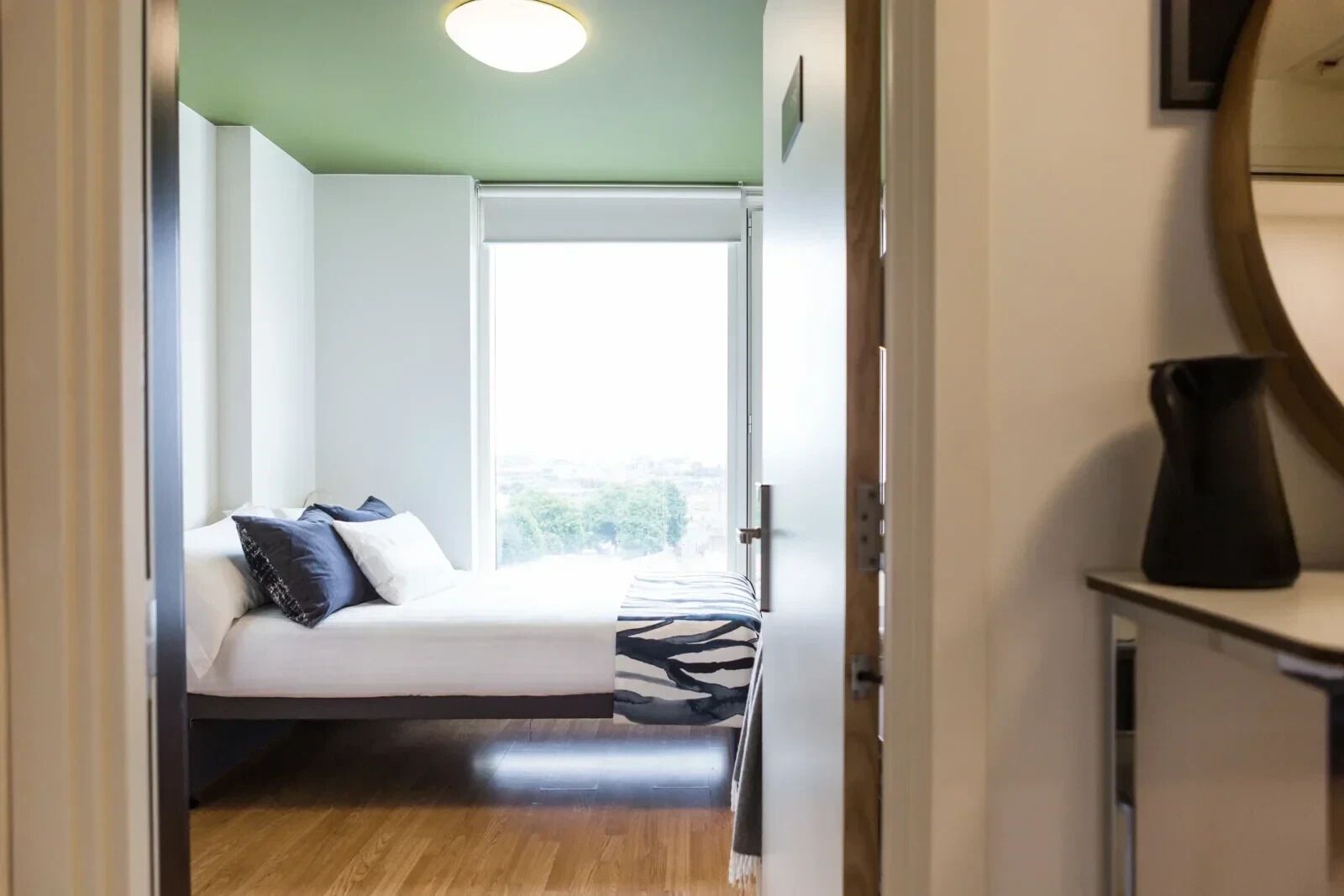 A bedroom with a bed, a window, and a view of the outdoors.