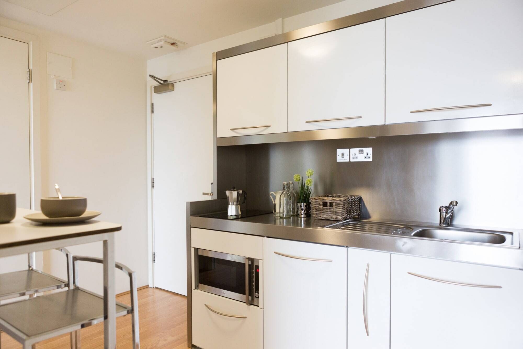 A modern kitchen with stainless steel appliances, white cabinetry, and a built-in oven.