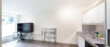 A modern kitchen with a built-in stove, a sink, and a dining area with a chair and a small table.