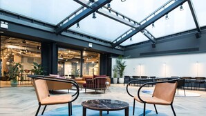 Un espacio interior amplio con techo alto, muebles modernos y ventanas grandes que dejan entrar luz natural.