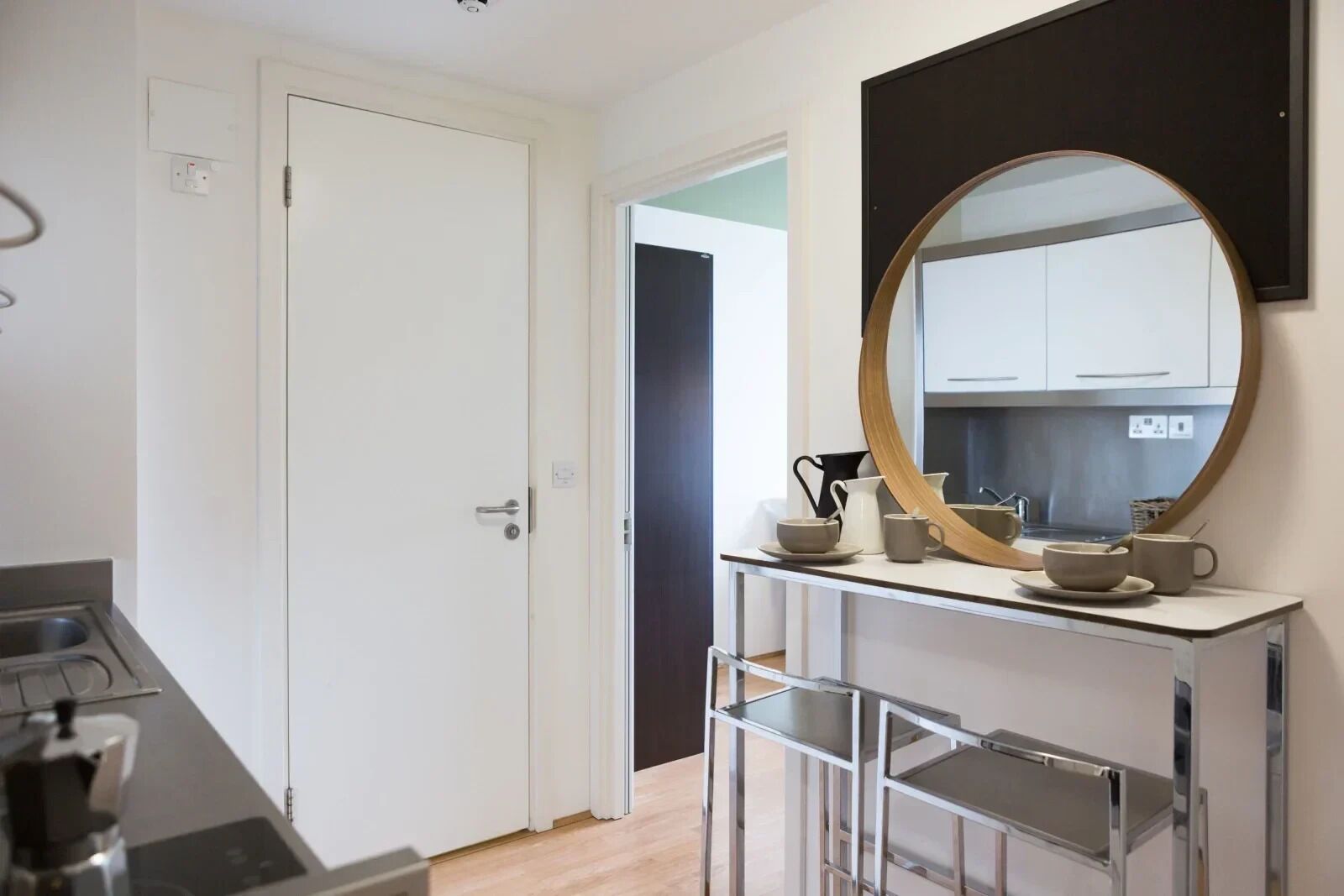 A modern kitchen with a round mirror, a coffee maker, and a sink.