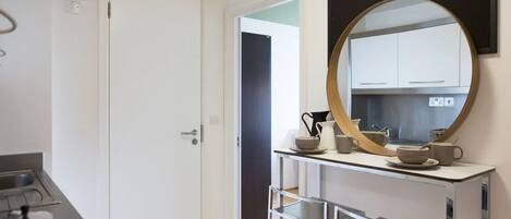 A modern kitchen with a round mirror, a coffee maker, and a sink.