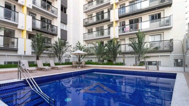 A residential building with a swimming pool, balconies, and outdoor seating. - Seu lindo lar no centro carioca (Rio de Janeiro)