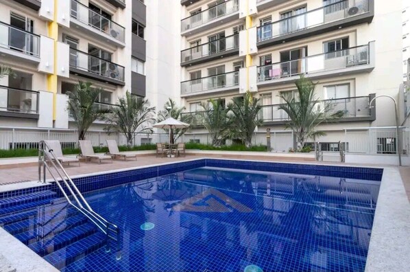 Een buitenzwembad, parasols bij het zwembad en ligstoelen