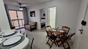 A dining area with a round table set for four, a sofa, and a balcony with a view. - Seu lindo lar no centro carioca (Rio de Janeiro)