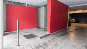 A modern building entrance with red walls, a glass door, and a tiled floor. - LMC 509 (Buenos Aires)