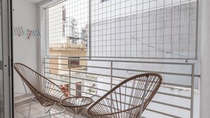 A balcony with two wicker chairs and a small table, overlooking a cityscape. - LMC 509 (Buenos Aires)