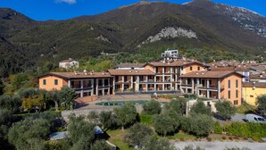 A hotel with multiple floors, outdoor swimming pool, and a mountainous backdrop. - Le Terrazze PT36 by Wonderful Italy (Toscolano Maderno)
