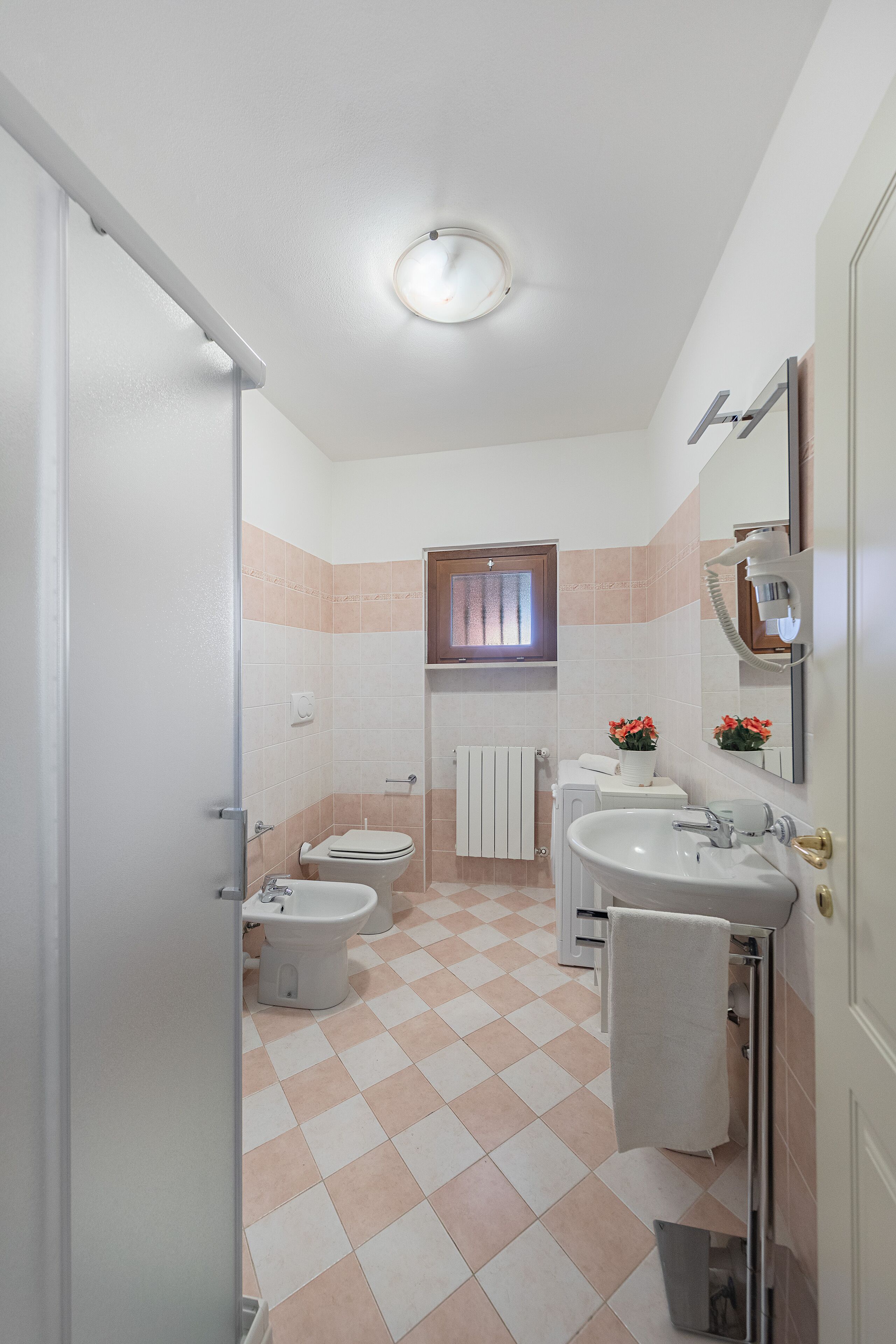A bathroom with a toilet, bidet, sink, and a mirror.