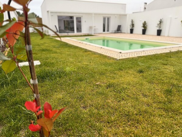 Ein modernes Haus mit Swimmingpool, gepflegtem Rasen und heller Fassade.