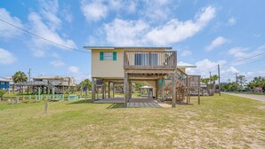 A two-story house with a wooden deck and a covered porch. - Gulf of Mexico Beach Cottage: Walk to Boat Ramp! (Horseshoe Beach)