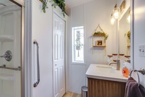 A bathroom with a white sink, a mirror, a towel rack, and a window with a view of greenery outside. - North Fairfield Family Home w/ Hot Tub & Porch! (North Fairfield)