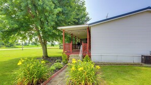 A covered porch with a view of a grassy yard and a building with a white exterior. - North Fairfield Family Home w/ Hot Tub & Porch! (North Fairfield)