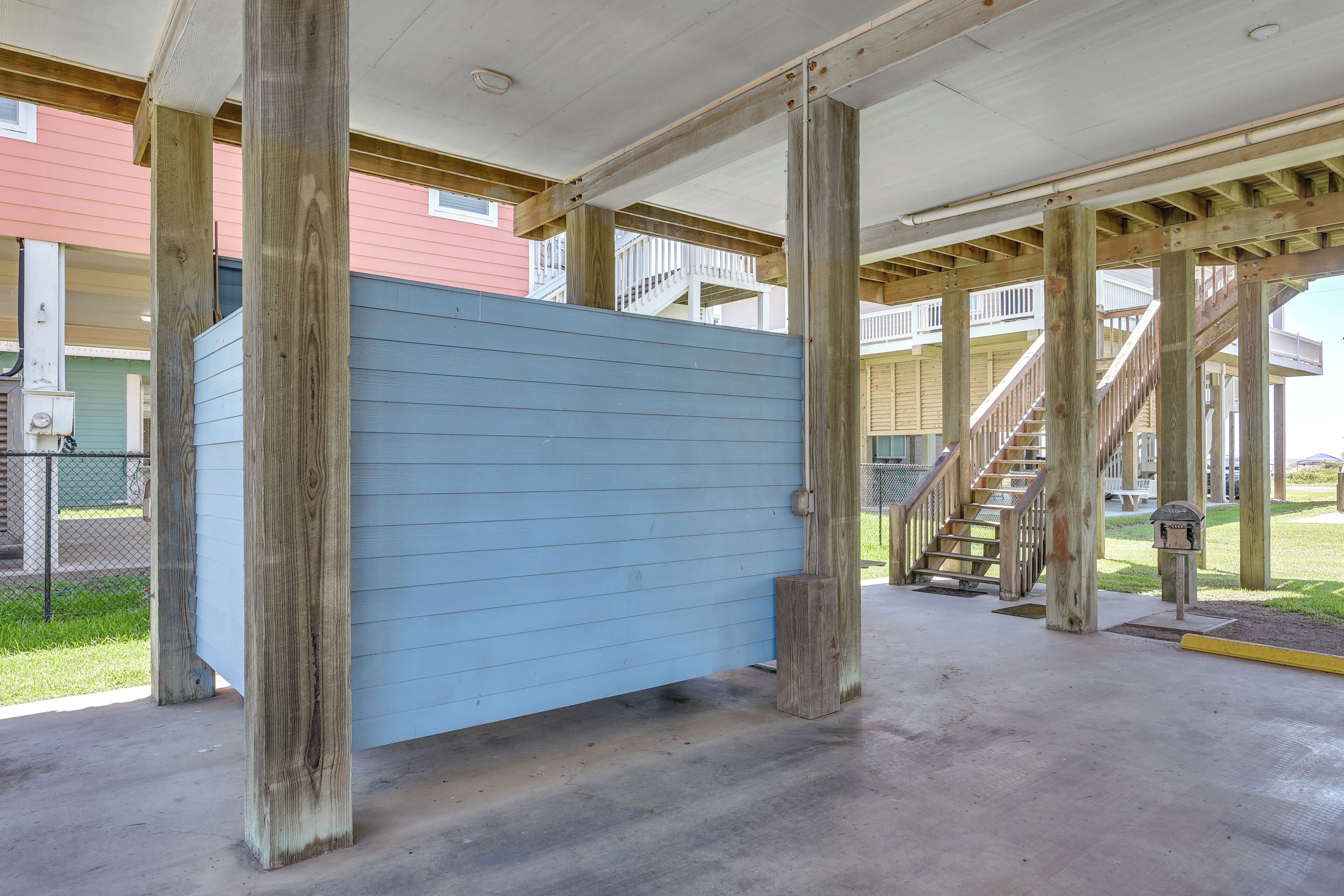 A building with a blue exterior, wooden beams, and a concrete floor.