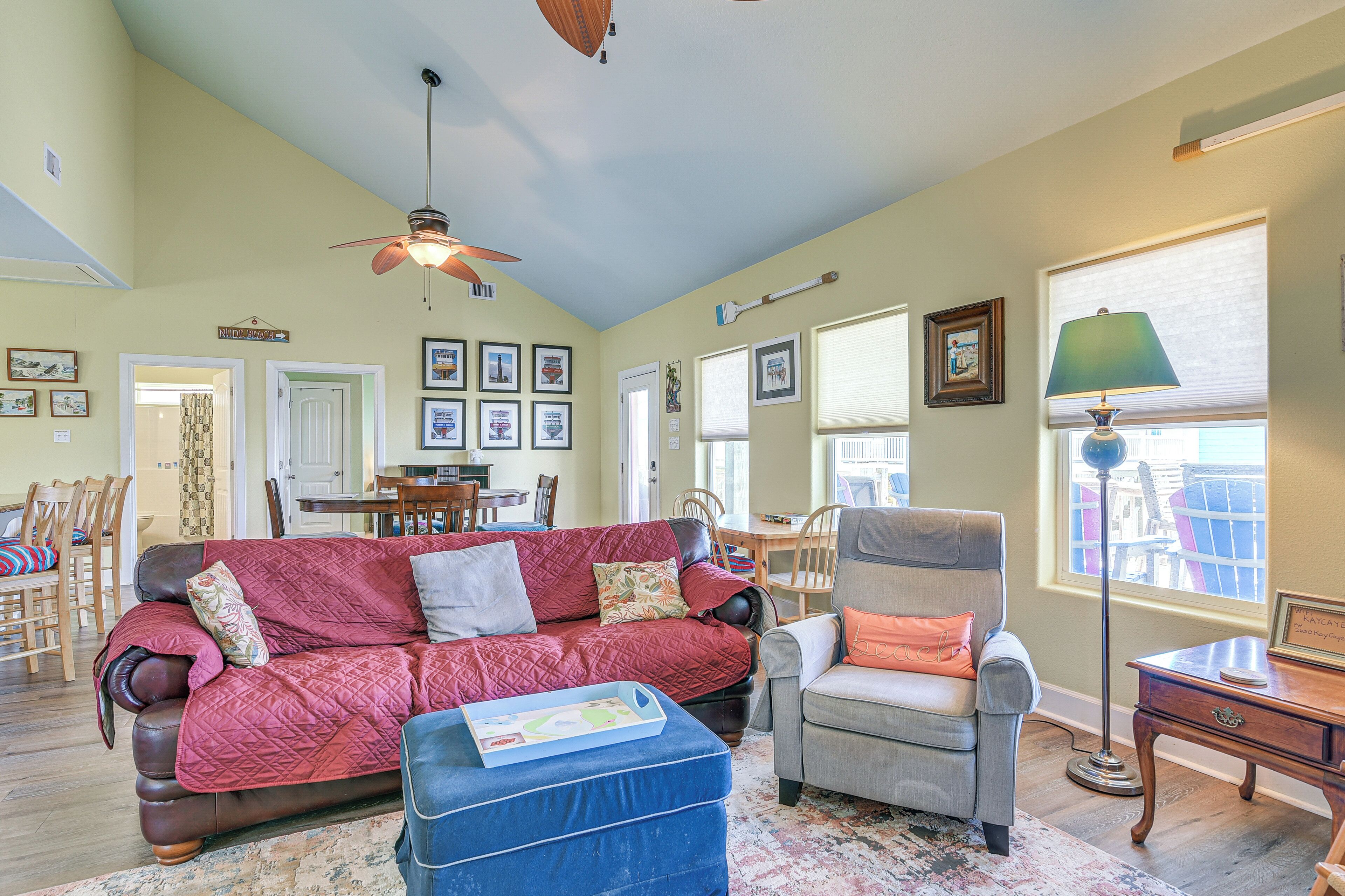 A living room with a red sofa, a blue ottoman, a grey armchair, and a wooden side table.