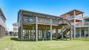 A multi-story building with a covered outdoor area, a staircase, and a view of the surrounding neighborhood. - Steps to Crystal Beach! Family & Pet-friendly Home (Port Bolivar)