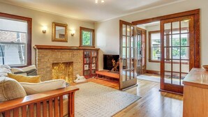 A cozy living room with a fireplace, wooden furniture, and a large window. - Cozy Cheyenne Home w/ Yard < 1 Mi to Downtown! (Cheyenne)