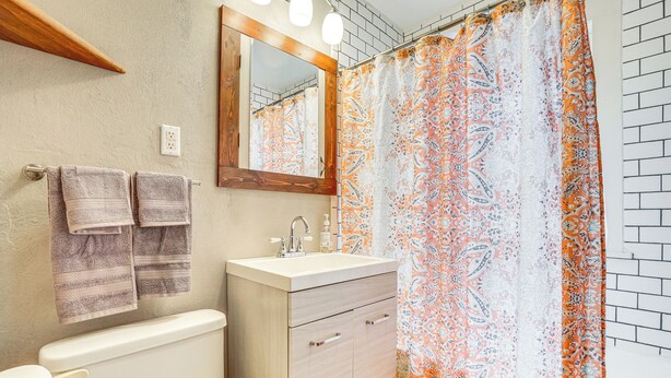 A bathroom with a toilet, sink, mirror, and shower curtain. - Cozy Cheyenne Home w/ Yard < 1 Mi to Downtown! (Cheyenne)