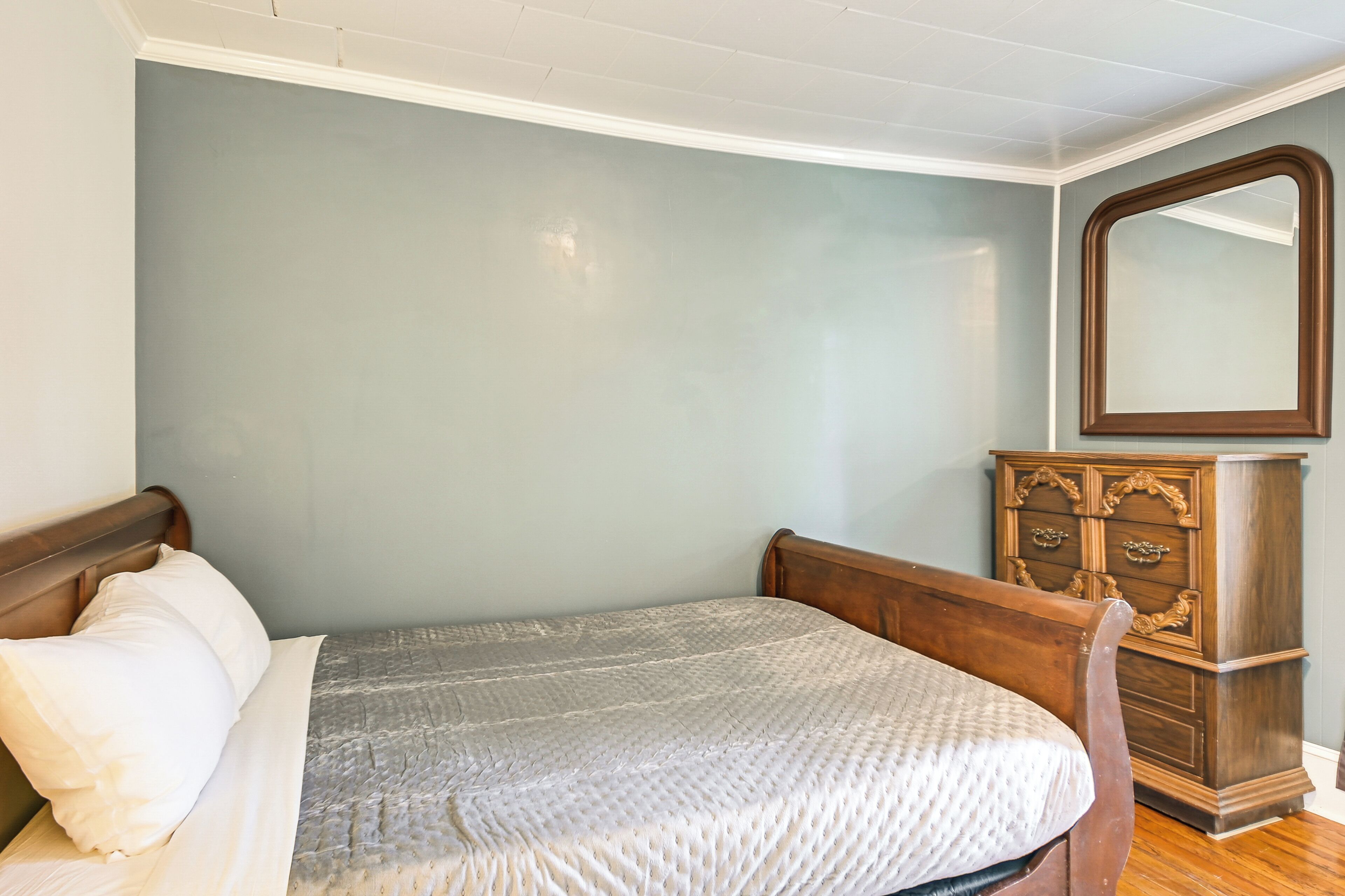 Quarto com uma cama, cômoda e espelho.
