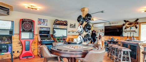A bar area with a dartboard, a pool table, and a wooden ceiling.