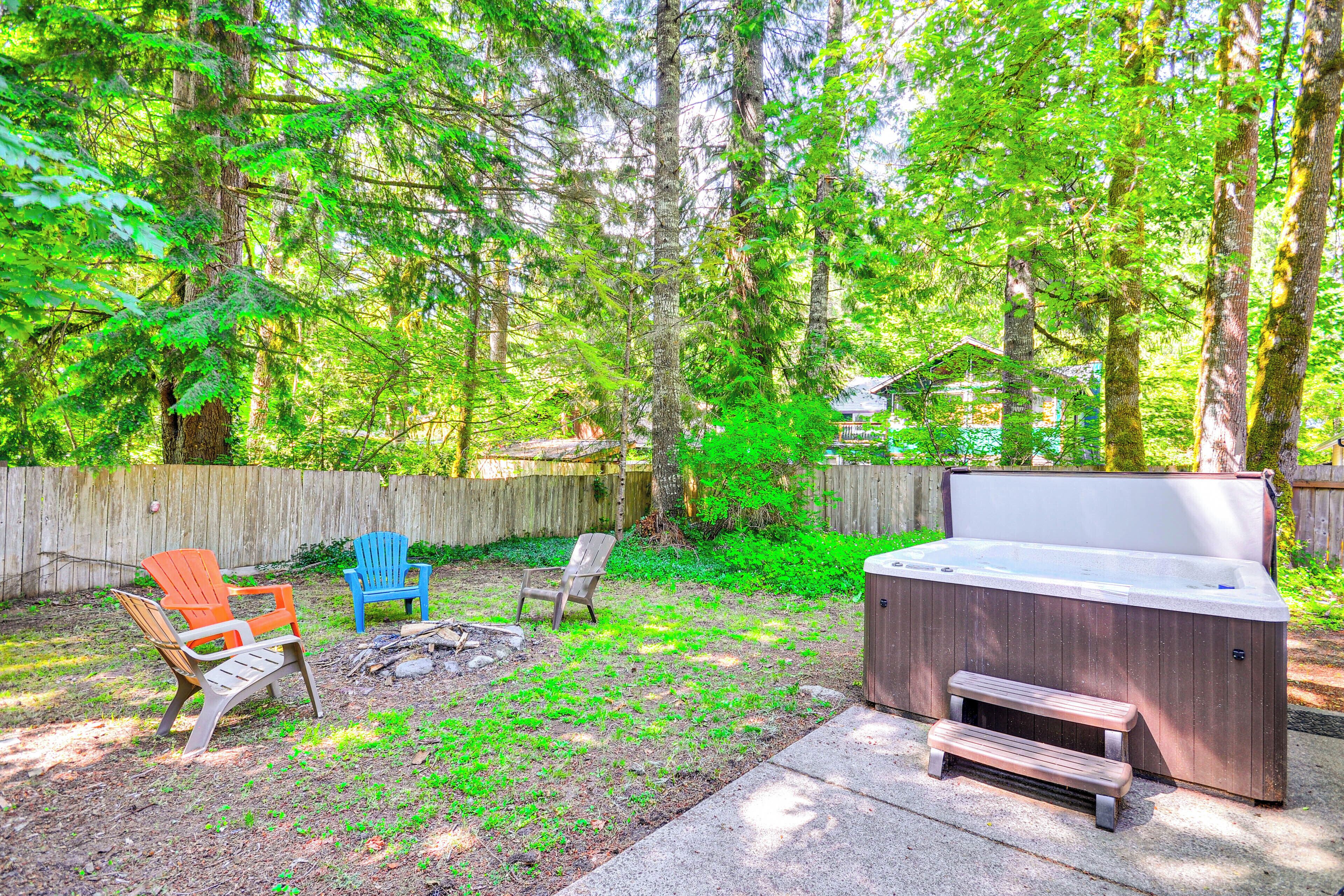 Un patio trasero con un jacuzzi, sillas de madera y una terraza de madera.