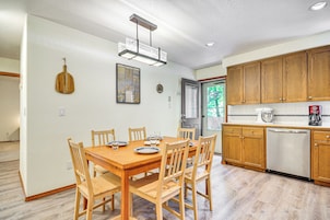 Un comedor con mesa y sillas de madera, una cocina con armarios de madera y una lámpara colgante moderna.