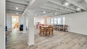 A spacious room with exposed ceilings, a dining area with wooden furniture, and large windows allowing natural light. - Charming Wolcott Cottage w/ Fire Pit & Mini Dock (Wolcott)