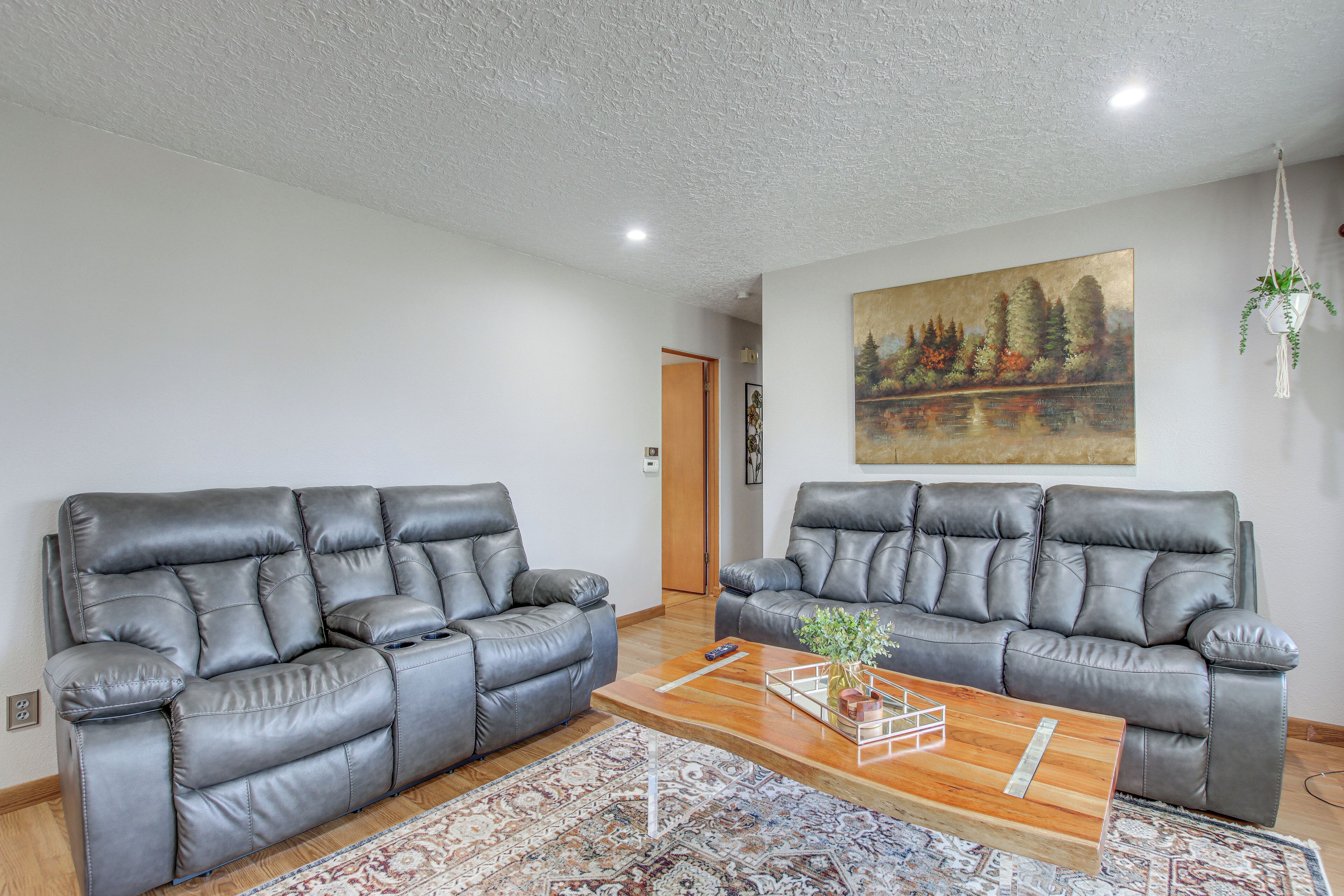 A living room with two grey leather sofas, a wooden coffee table, and a patterned rug.