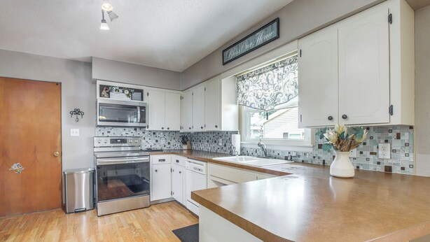 A kitchen with white cabinets, stainless steel appliances, a wooden countertop, and a backsplash with a mosaic tile design. - Walk to Park: Waterloo Home w/ Furnished Deck (Waterloo)