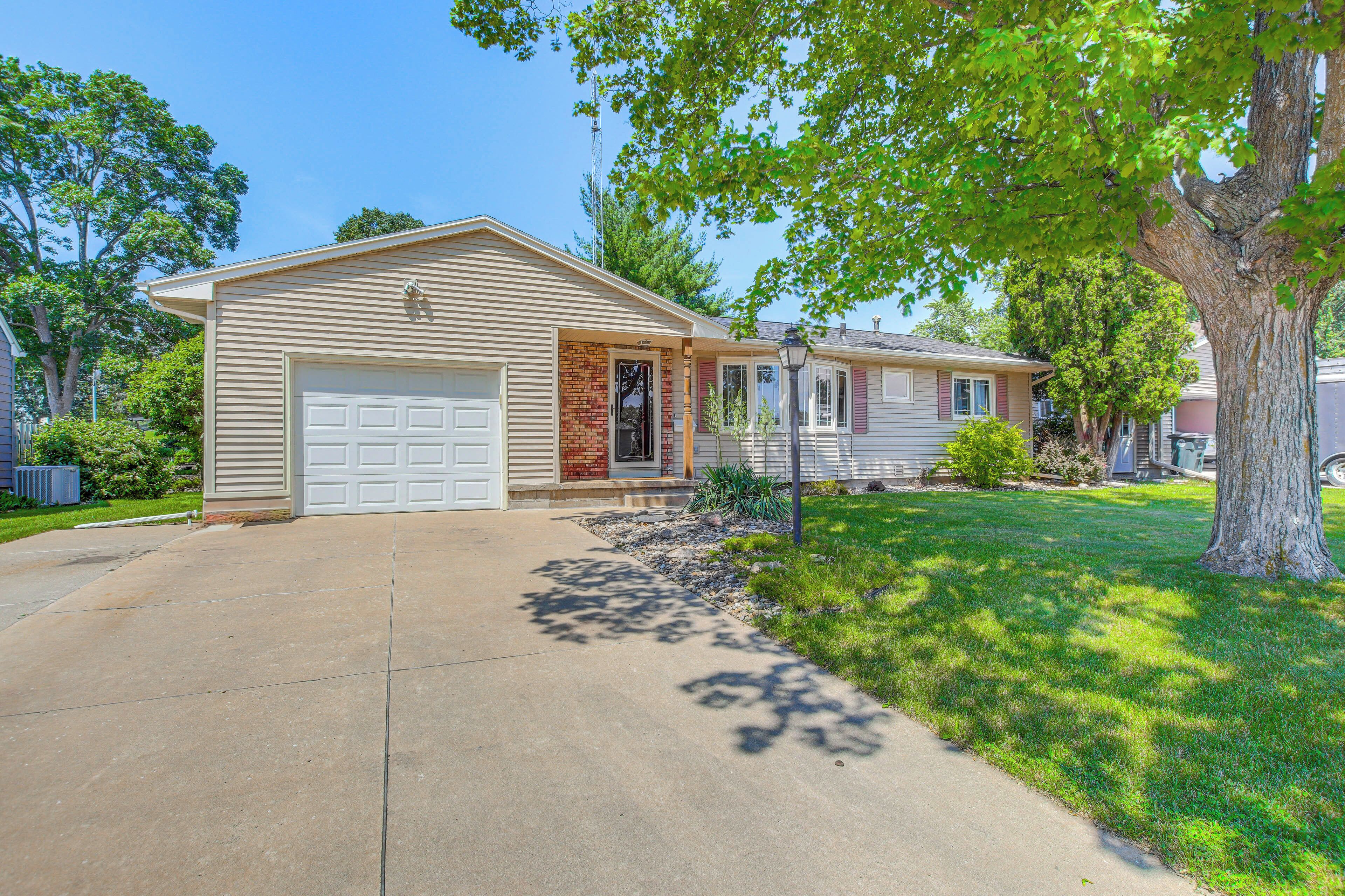 A two-story house with a garage, a front porch, and a lawn.
