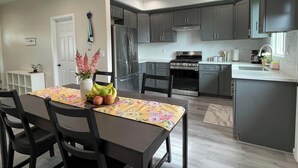 A modern kitchen with dark cabinets, stainless steel appliances, and a dining area with a table set for two.