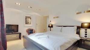 Ein Hotelzimmer mit Bett, Nachttischlampen, Fernseher, Sessel und Tür.