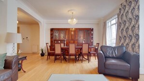 Ein geräumiges Wohnzimmer mit Esstisch aus Holz, einer Ledersofa und einer Chandel.