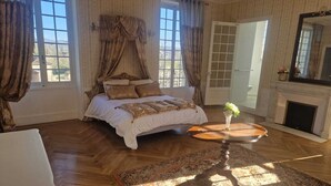 Een slaapkamer met een groot bed, een open haard en uitzicht op de omgeving.