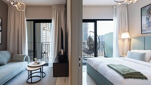 Ein Hotelzimmer mit Bett, Sofa, kleinem Tisch, Stuhl und einem Balkon mit Stadtblick.