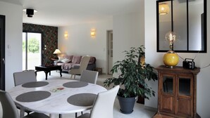 Un salon moderne comprenant un coin repas, une grande plante en pot et un meuble en bois abritant une radio.