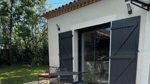 Un espace patio aménagé avec une table et des chaises, un pot de fleurs et une pelouse artificielle verte.