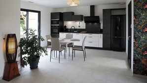 Une cuisine moderne avec des meubles de couleur sombre, une table de salle à manger ronde et une plante en pot.