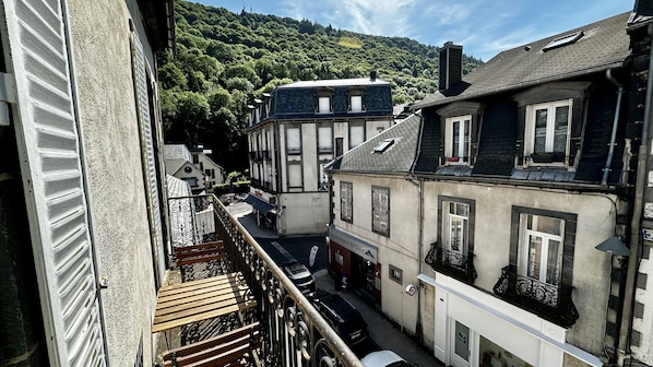 Una calle estrecha flanqueada por edificios, un balcón con barandilla de metal y un letrero que dice 'La Concierge du Sancy'.