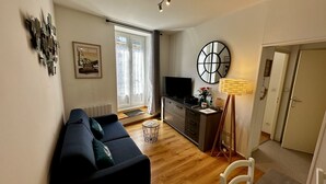 Una sala de estar con un sofá, un televisor, una lámpara y un cuadro en la pared.
