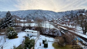 Un pueblo cubierto de nieve con casas, un pequeño edificio blanco y una vía de tren.