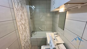Un baño con cabina de ducha de vidrio, lavamanos con espejo y paredes de azulejos.