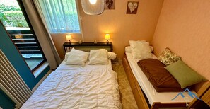 A bedroom with a bed, bedside lamps, a window, and a view of greenery outside. - Le Pradet A 781 - Mont Dore 4 pers (Mont-Dore)