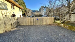 A gravel driveway leading to a wooden fence with a blue parking sign.