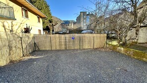 Uma entrada de cascalho que leva a uma cerca de madeira com uma placa de estacionamento azul.